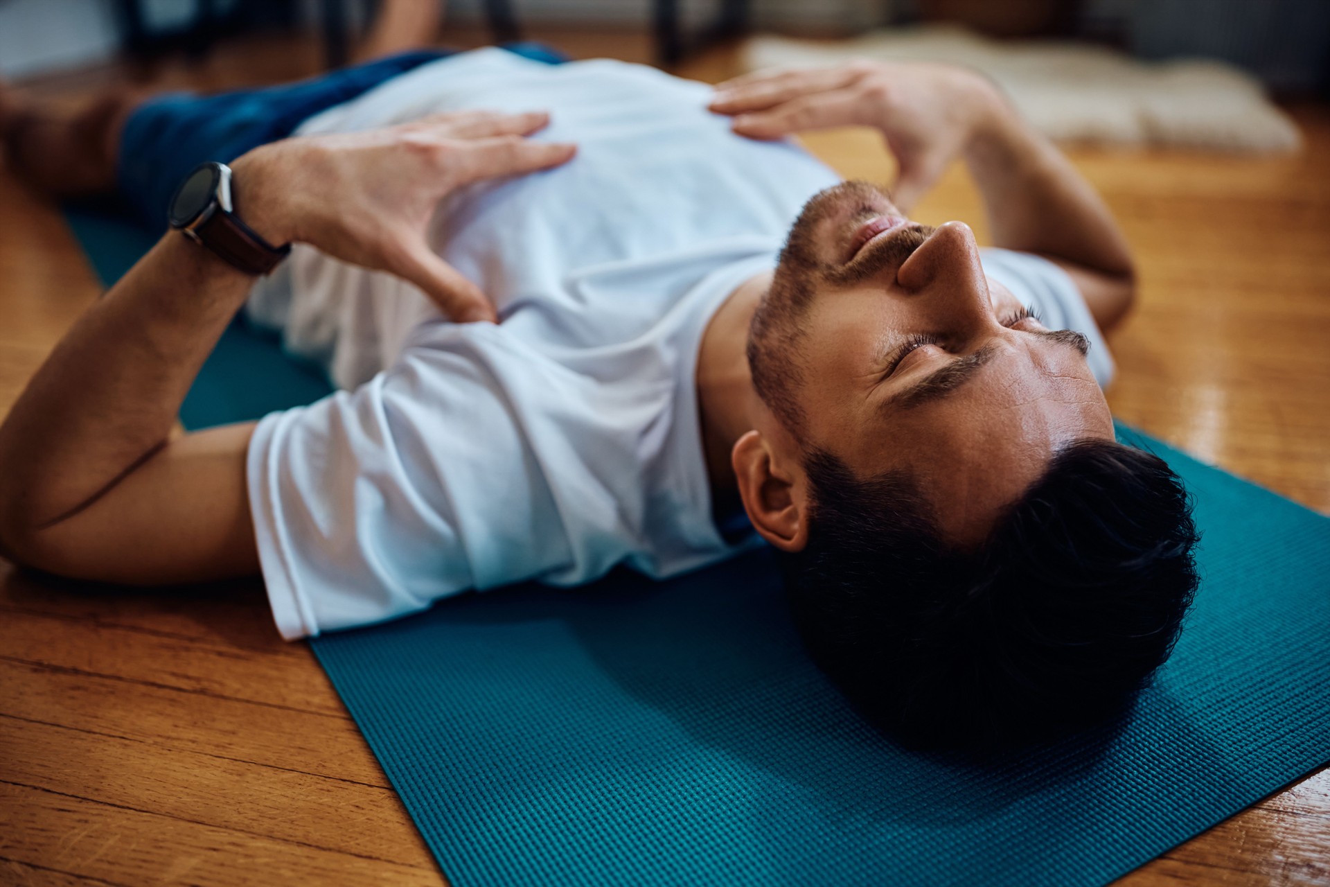 Exhausted sportsman resting on the floor during home workout.